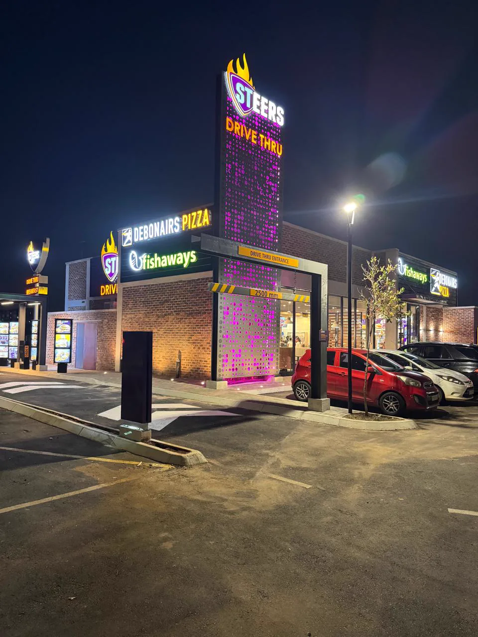 Illuminated Steers drive-thru pylon at night